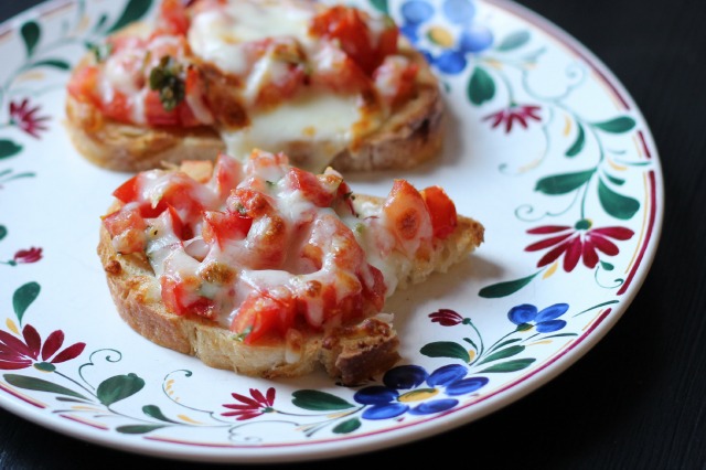 broiled bruschetta on a plate with a bite missing