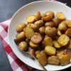 large serving bowl of roast potatoes with red checked cloth