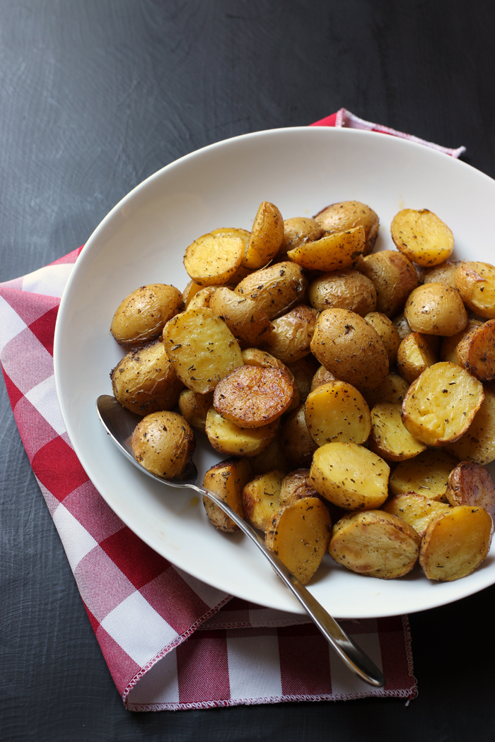 large serving bowl of roast potatoes with red checked cloth