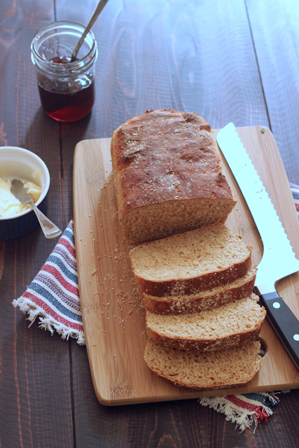 A loaf of bread sliced on wooden cutting board