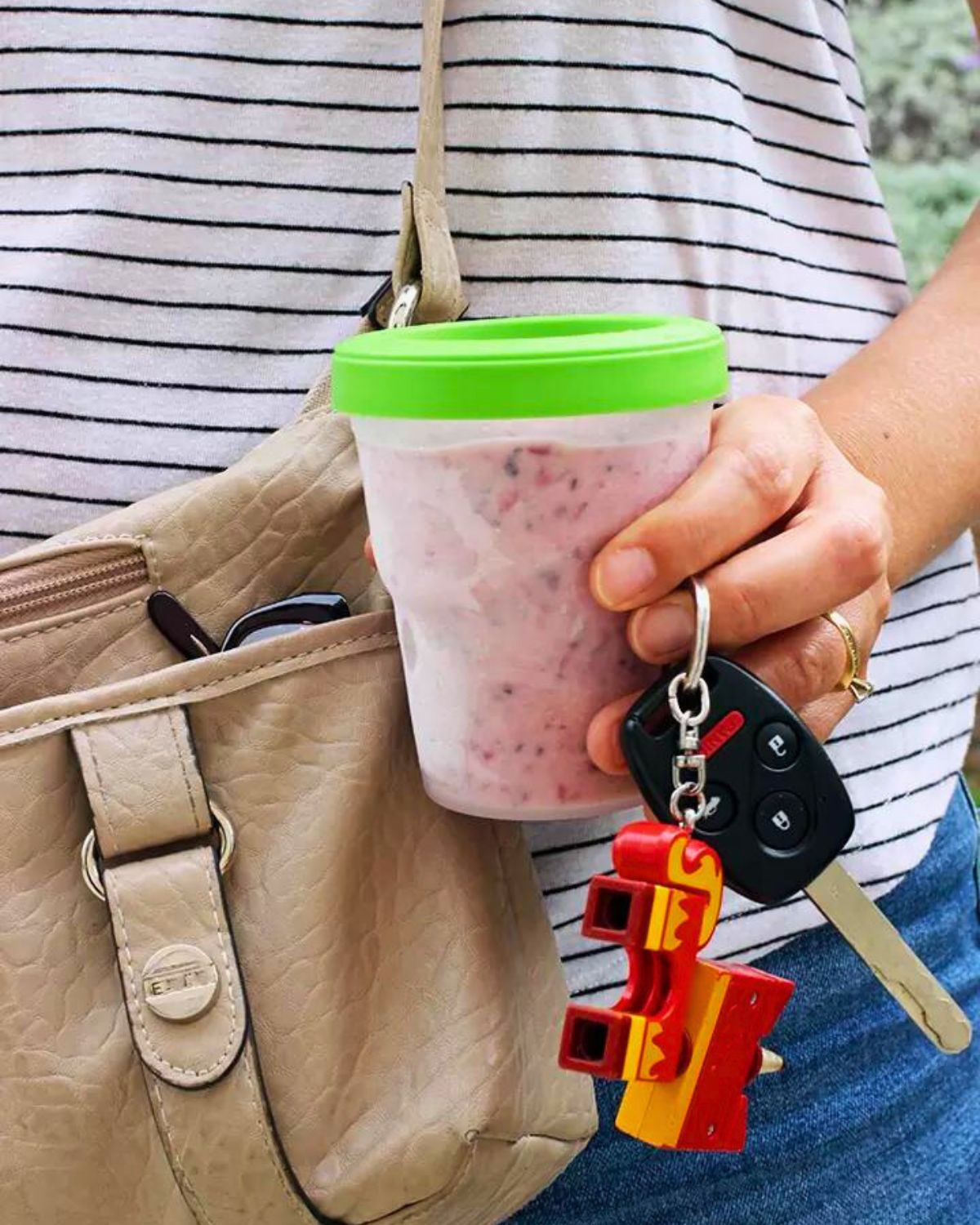 woman holding a smoothie with purse and keys in her hand.