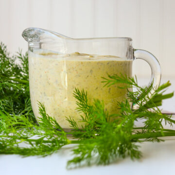 greek yogurt dressing in small pitcher with sprigs of dill.