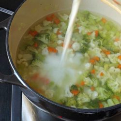 pouring milk into pot of vegetable soup