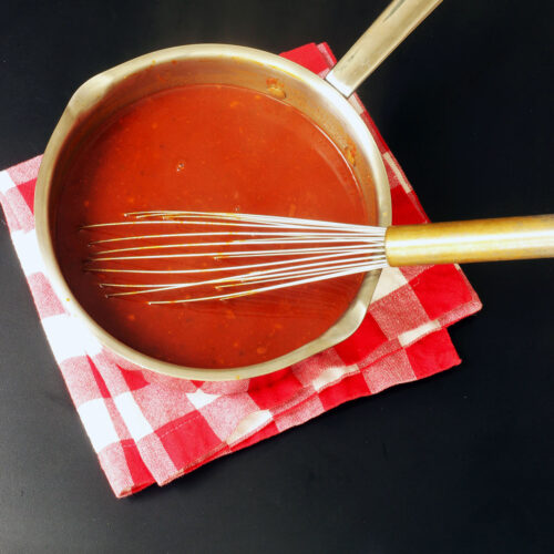 pot of enchilada sauce with metal whisk