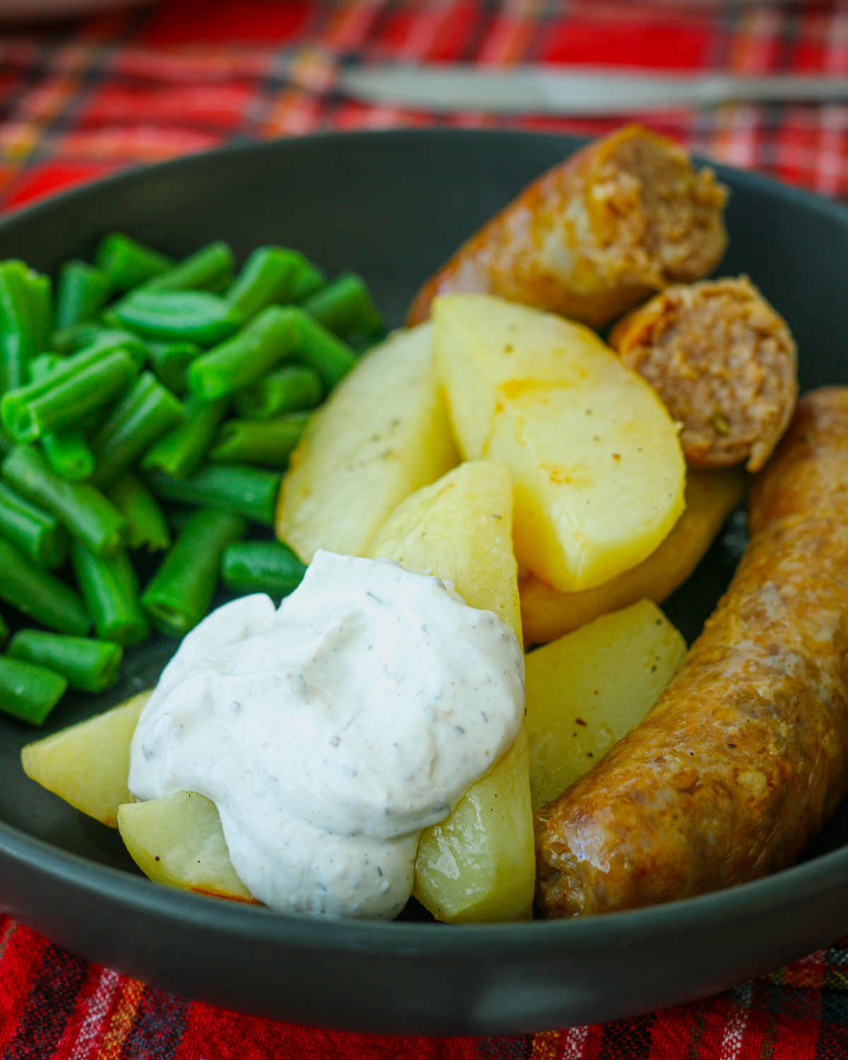 dinner plate with sausage, potatoes, green beans, and cream sauce.