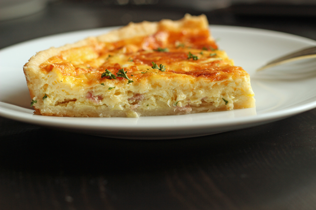 side view of Ham and Gruyere Quiche with Leeks on a white plate