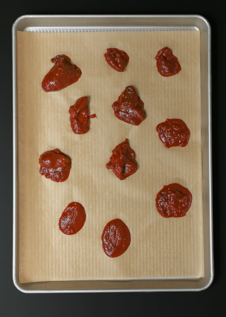 chipotles and sauce spread out on a parchment lined sheet pan.