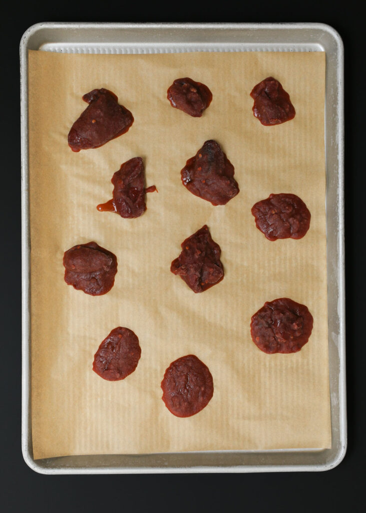 frozen chipotles and sauce on parchment-lined tray.