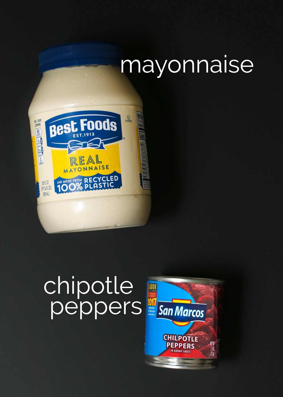 ingredients for making homemade chipotle mayo laid out on a black surface.