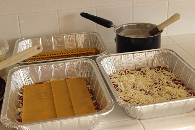 lasagna noodles layered in metal containers for freezing