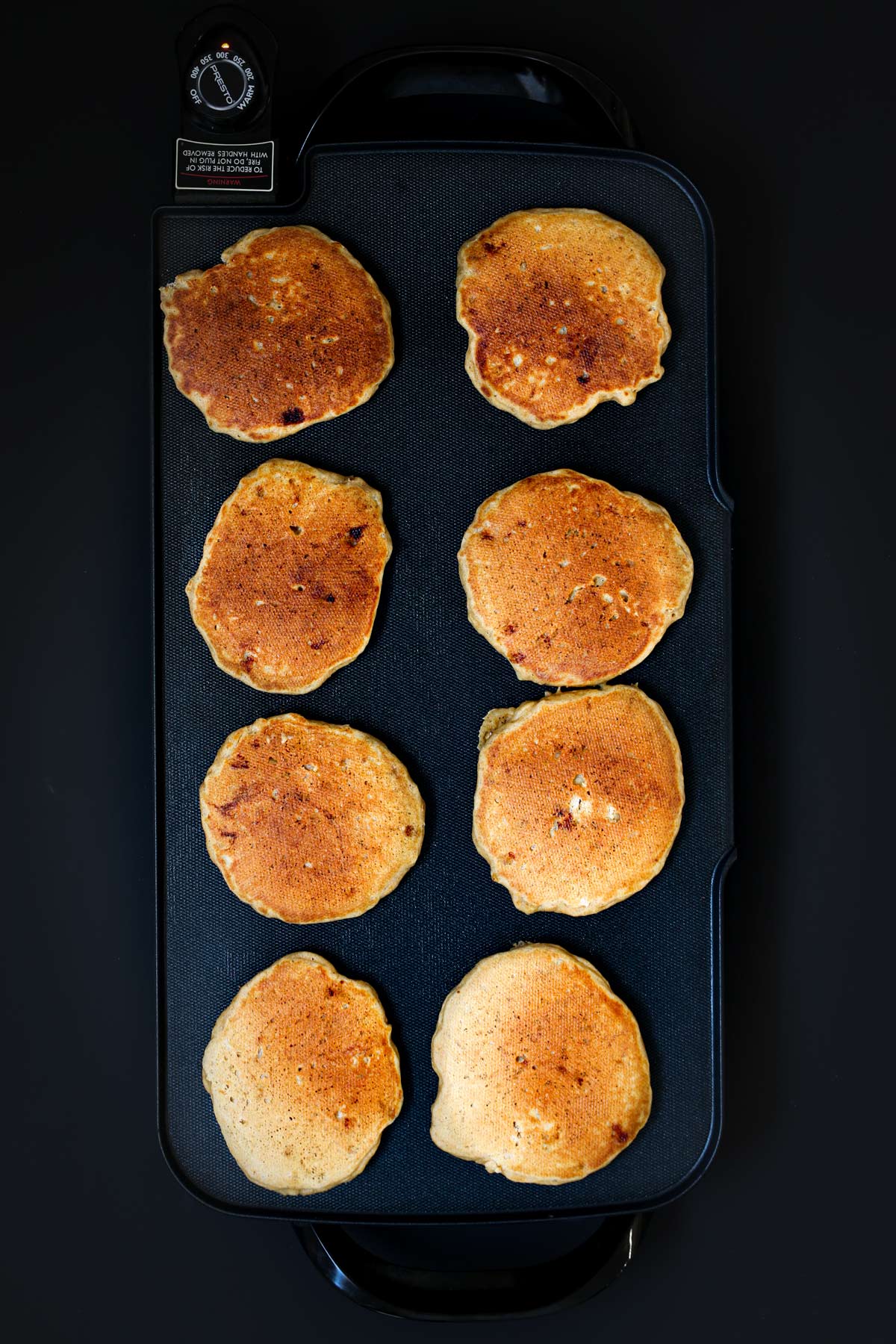 8 cooked banana whole wheat pancakes on hot griddle.