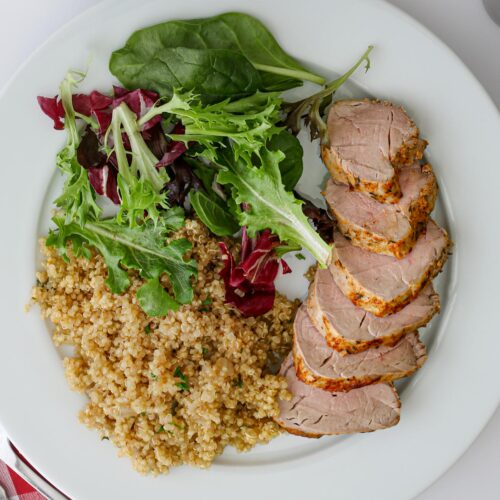 dinner plate with quinoa pilaf, salad, and pork tenderloin.