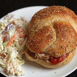 A plate with coleslaw and pulled pork sandwich