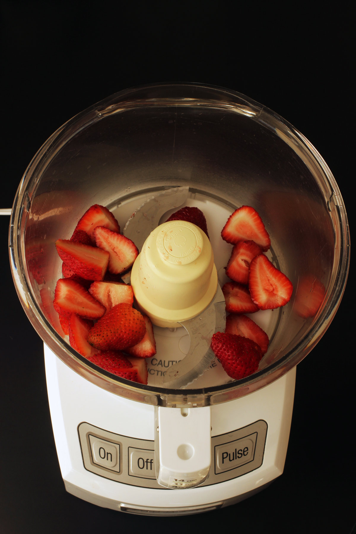strawberries in bowl of food processor with metal blade