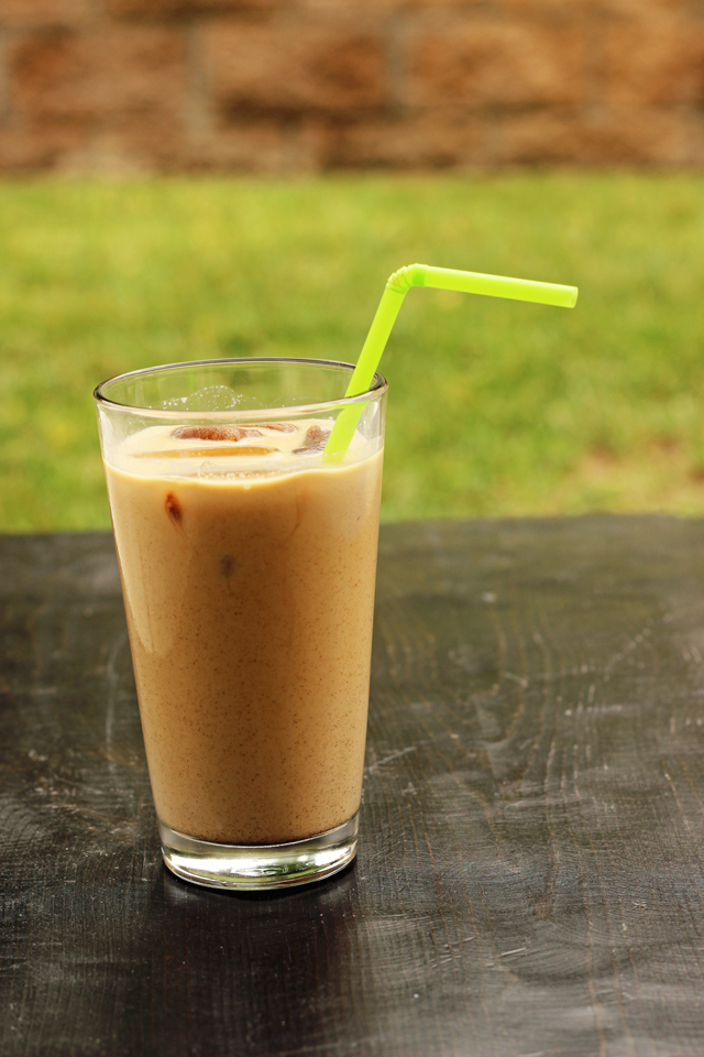 A cup of iced coffee on a table in the backyard.