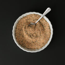 small white dish of cajun spice blend on black table with a small spoon.
