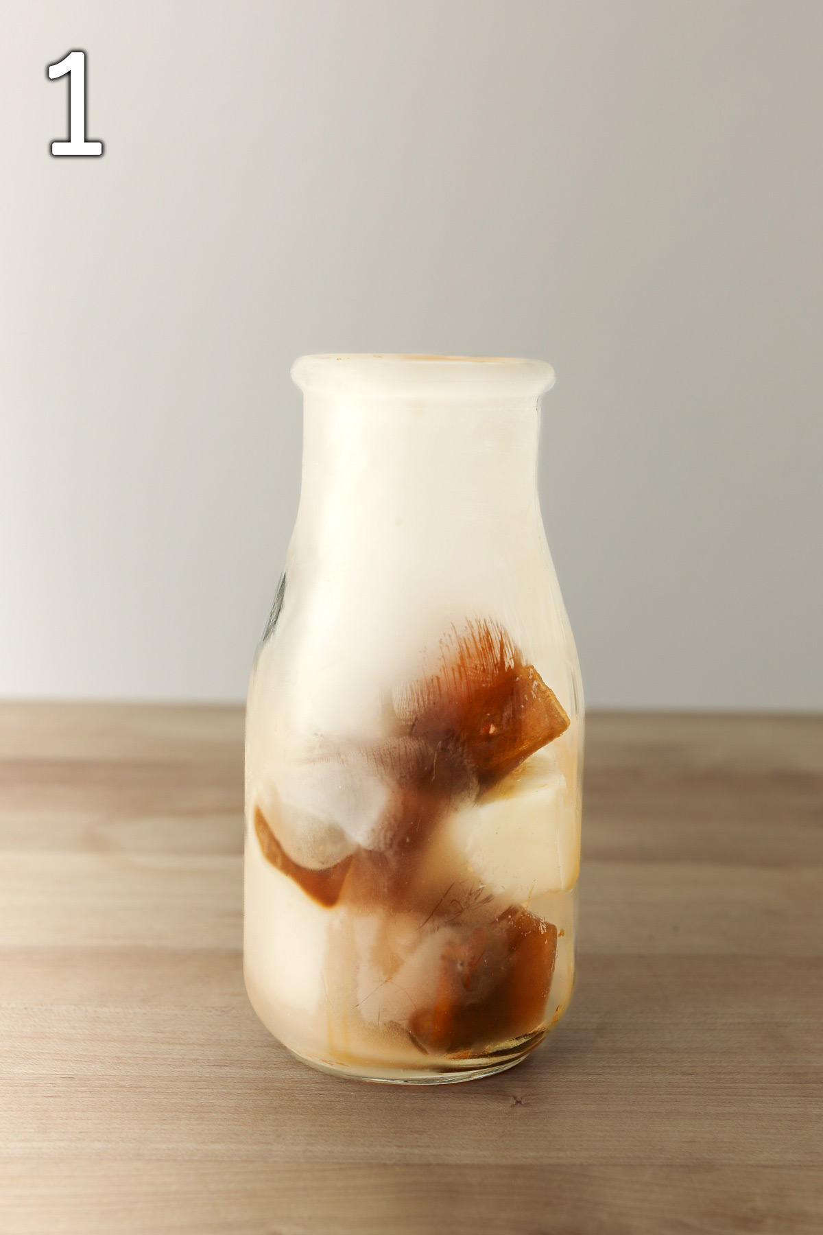 iced coffee and milk cubes in frosted milk glass.