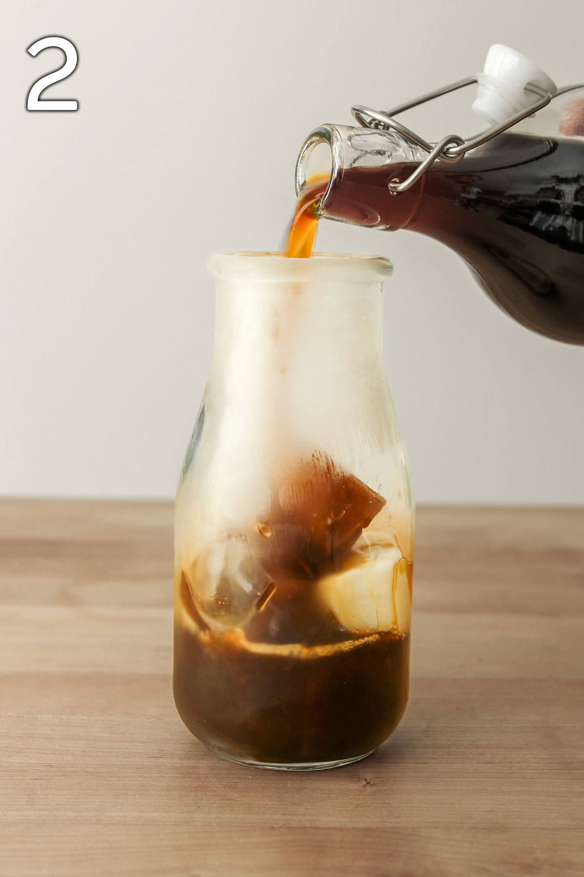 pouring coffee over ice in milk bottle.
