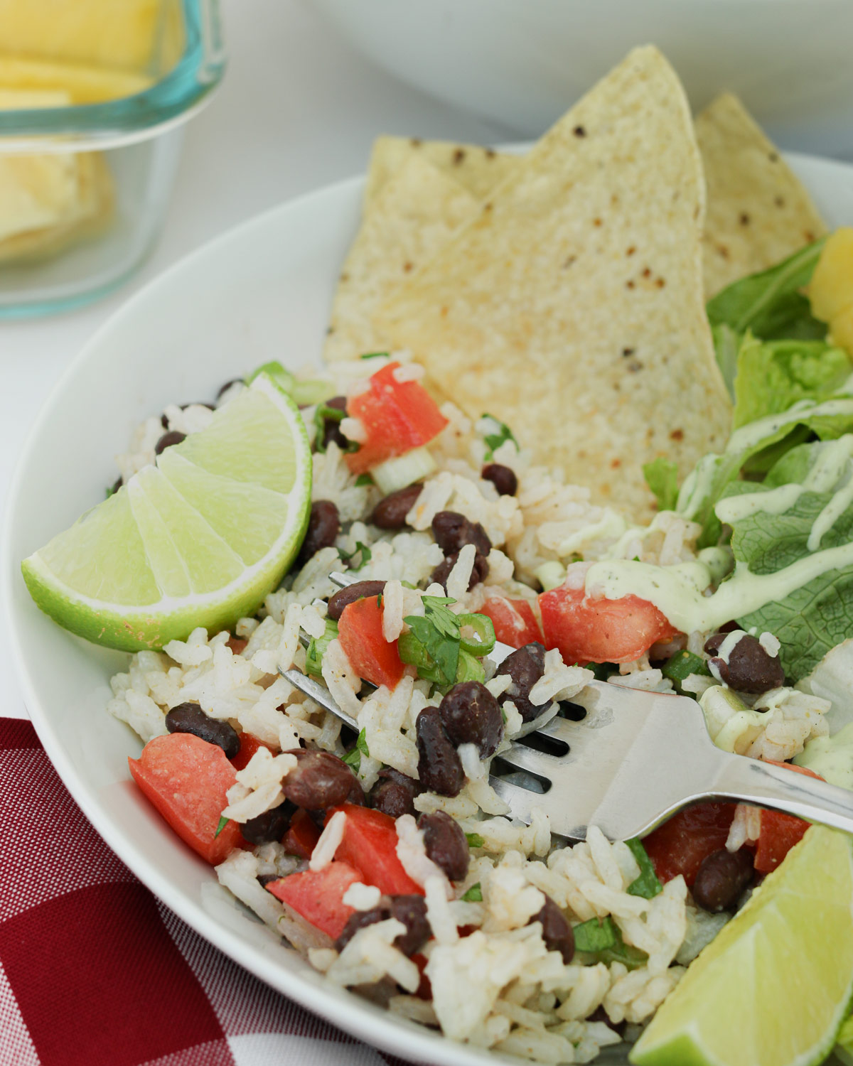 bowl of rice and bean salad with chips and a lime wedge.