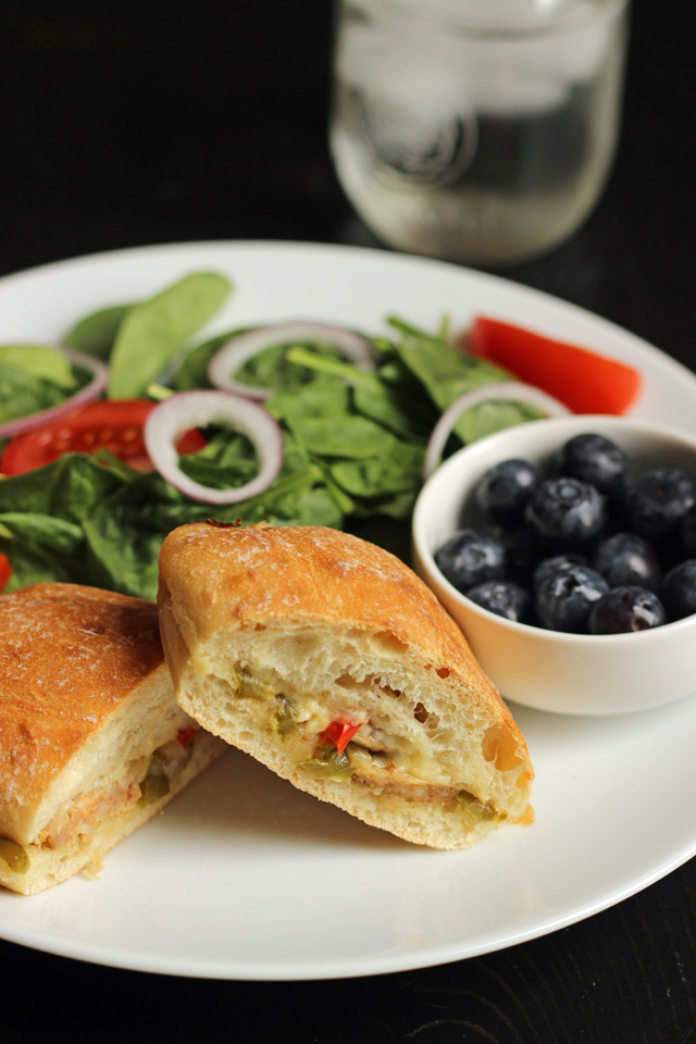 halves of sausage sandwich on plate with salad