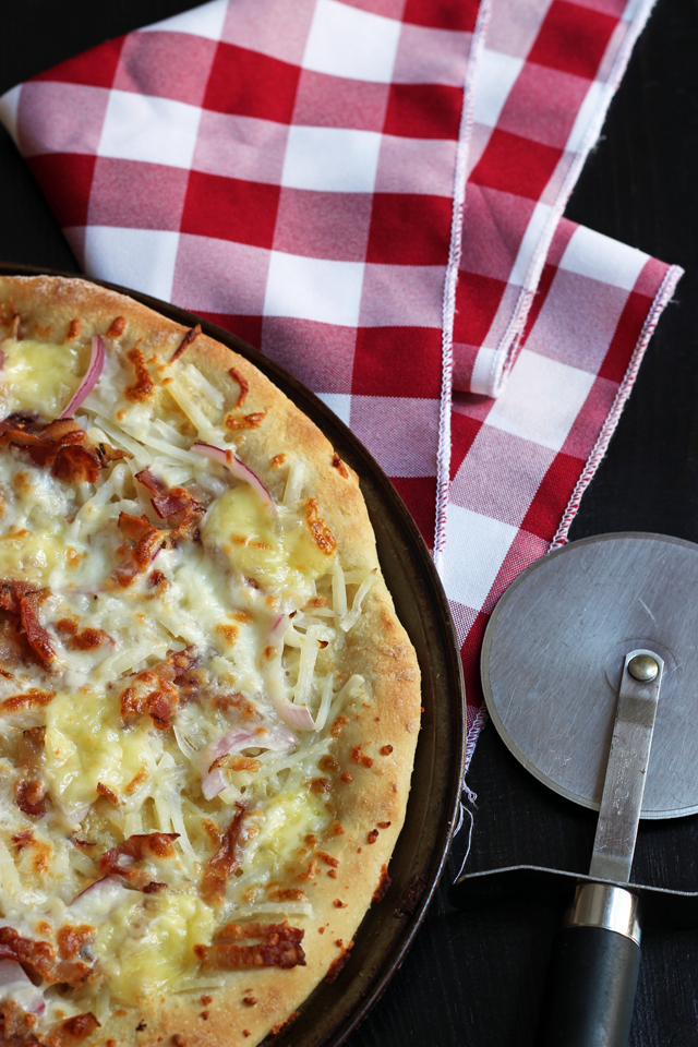 Tartiflette Pizza on table with pizza cutter