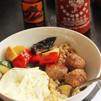 fried egg on a breakfast bowl with vegetables and sausage balls