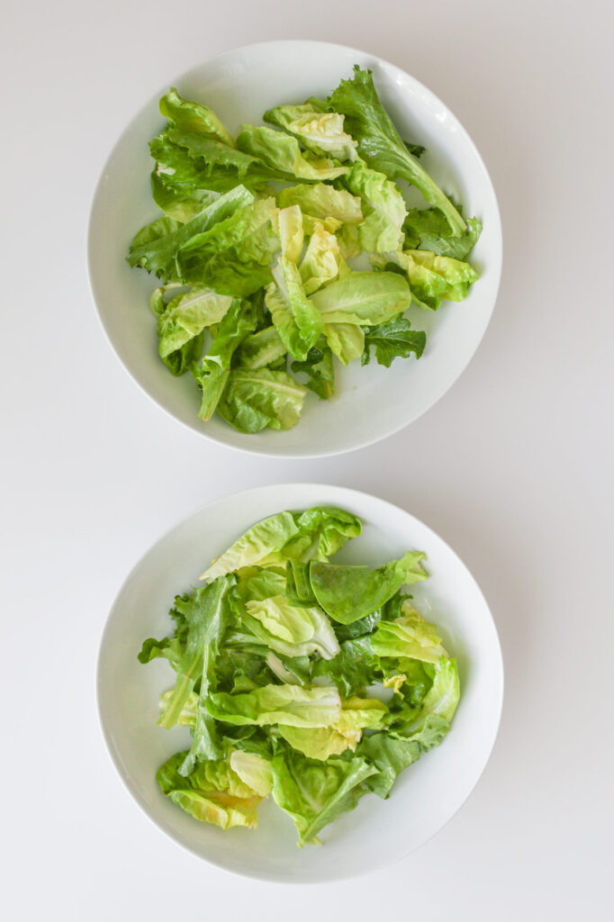 dressed salad divided into white dishes.