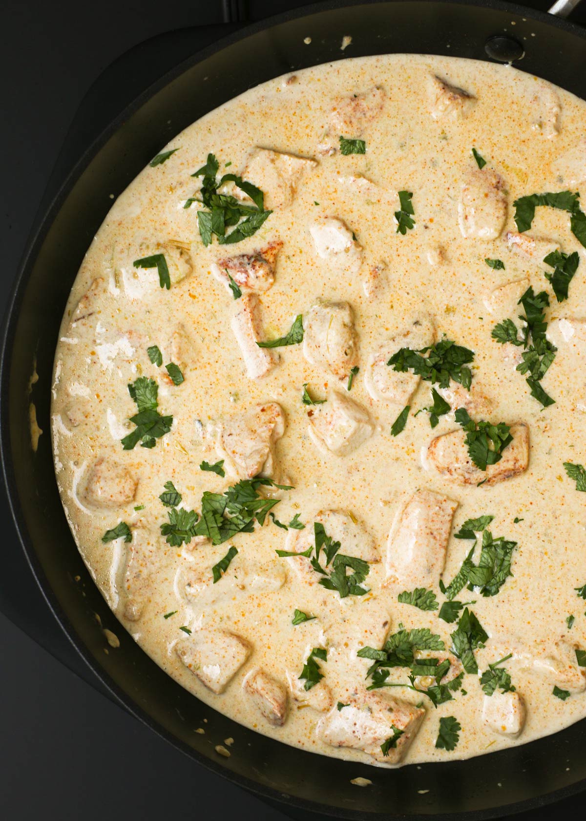 overhead shot of sour cream chicken and sauce in skillet topped with cilantro.