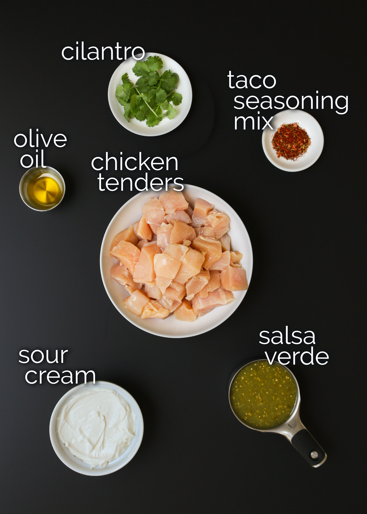 ingredients for sour cream chicken laid out on a black table top.