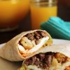 burrito śniadaniowe przekrojone na pół, dzbanek soku pomarańczowego