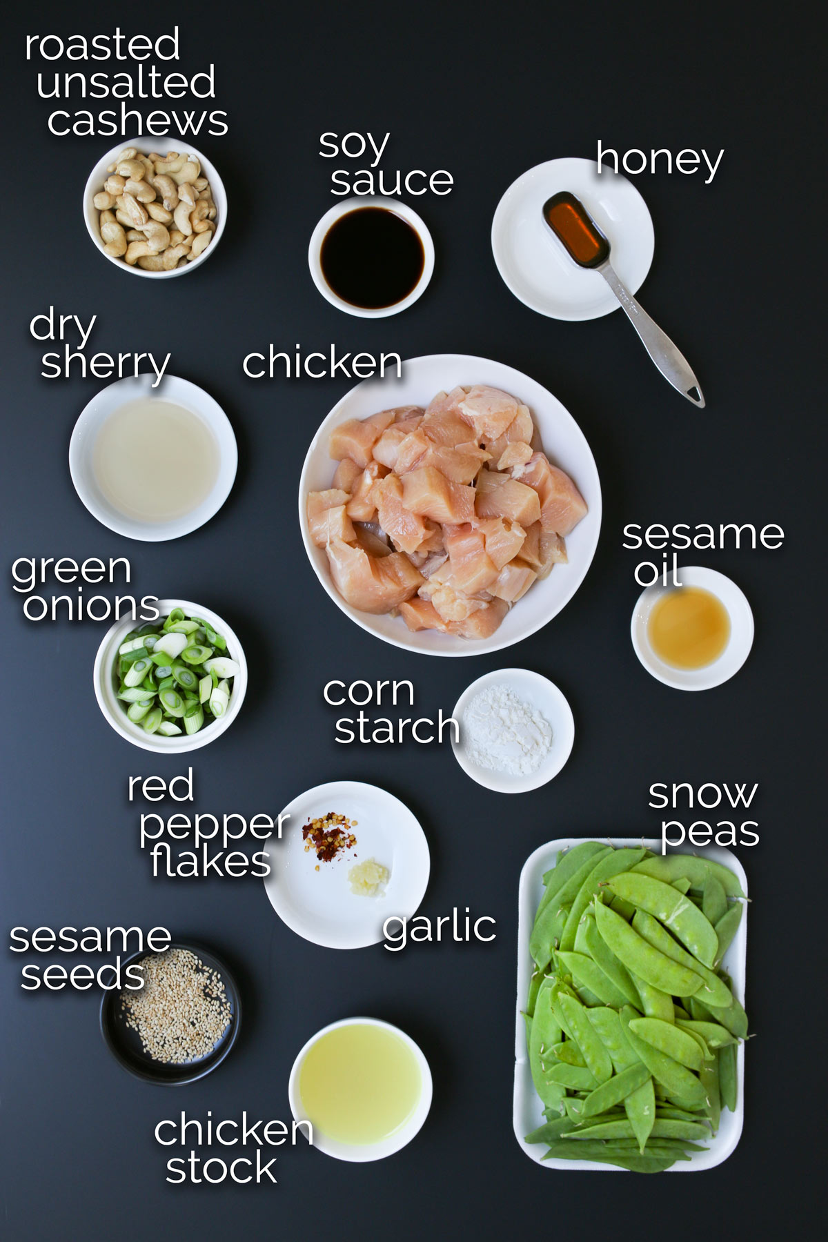 ingredients for cashew chicken laid out on a black table.