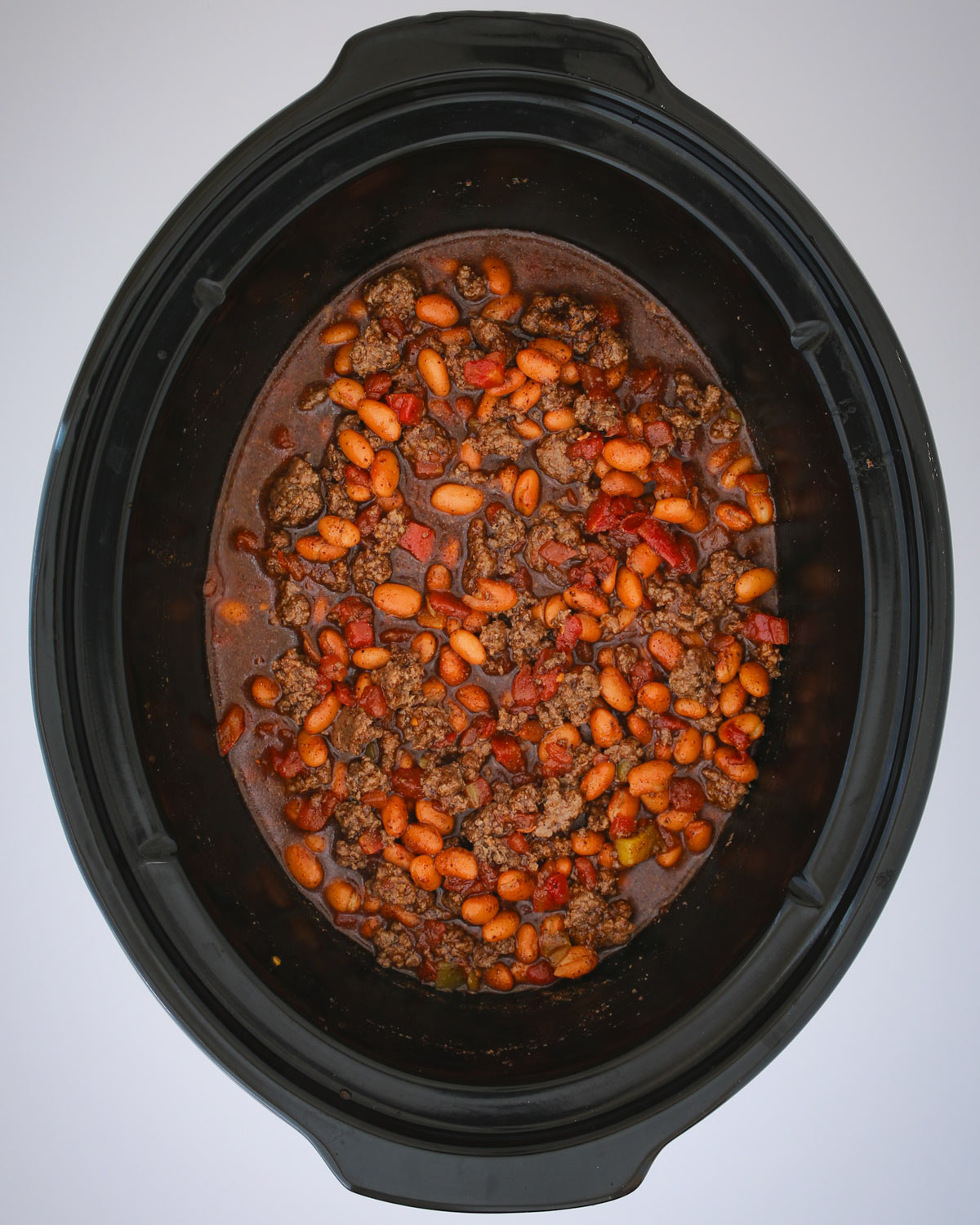 all the beans, meat, and spices mixed in the slow cooker.
