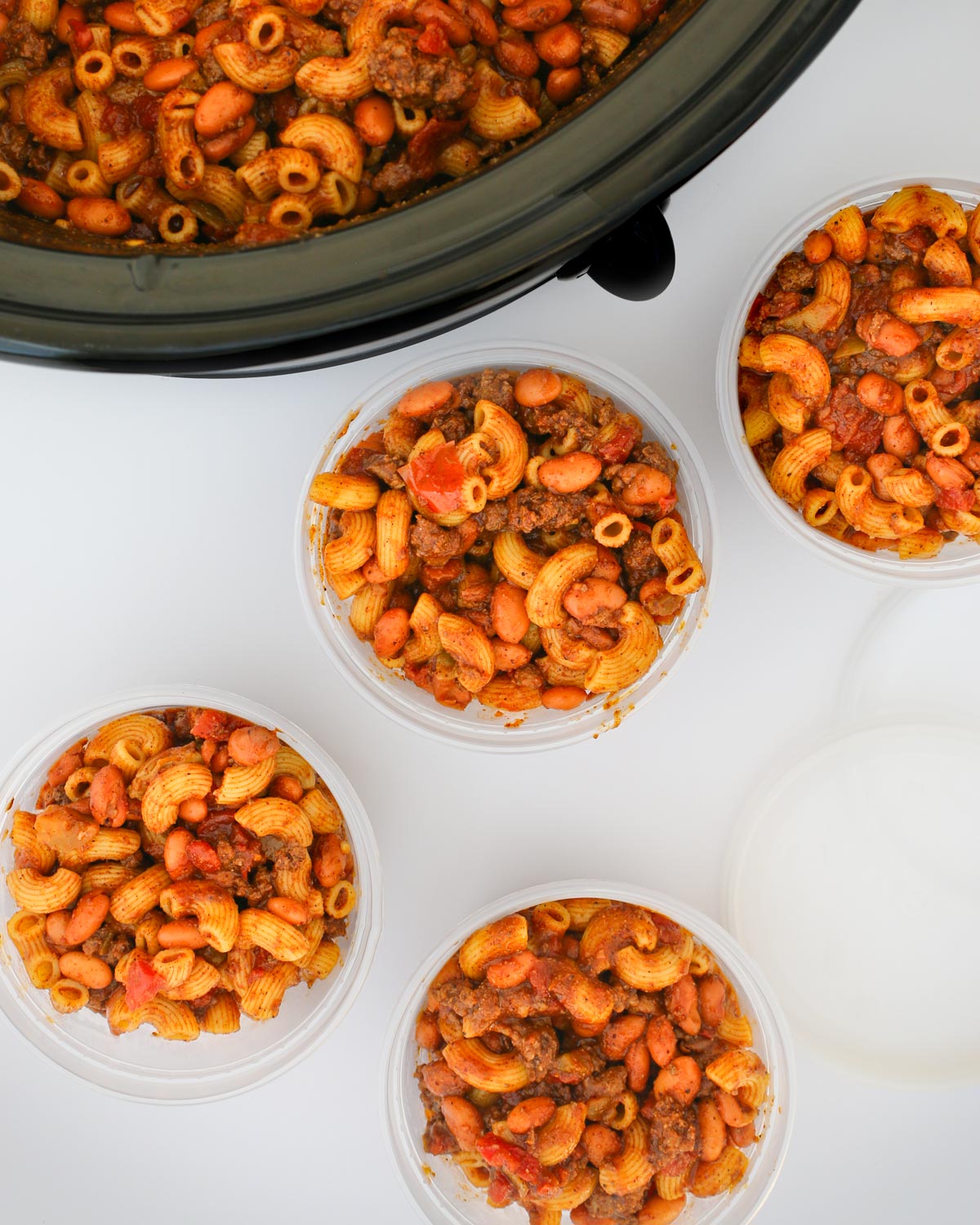 chili mac in meal prep containers next to slow cooker.