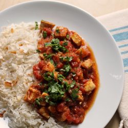 A plate of rice and chicken tikka masala