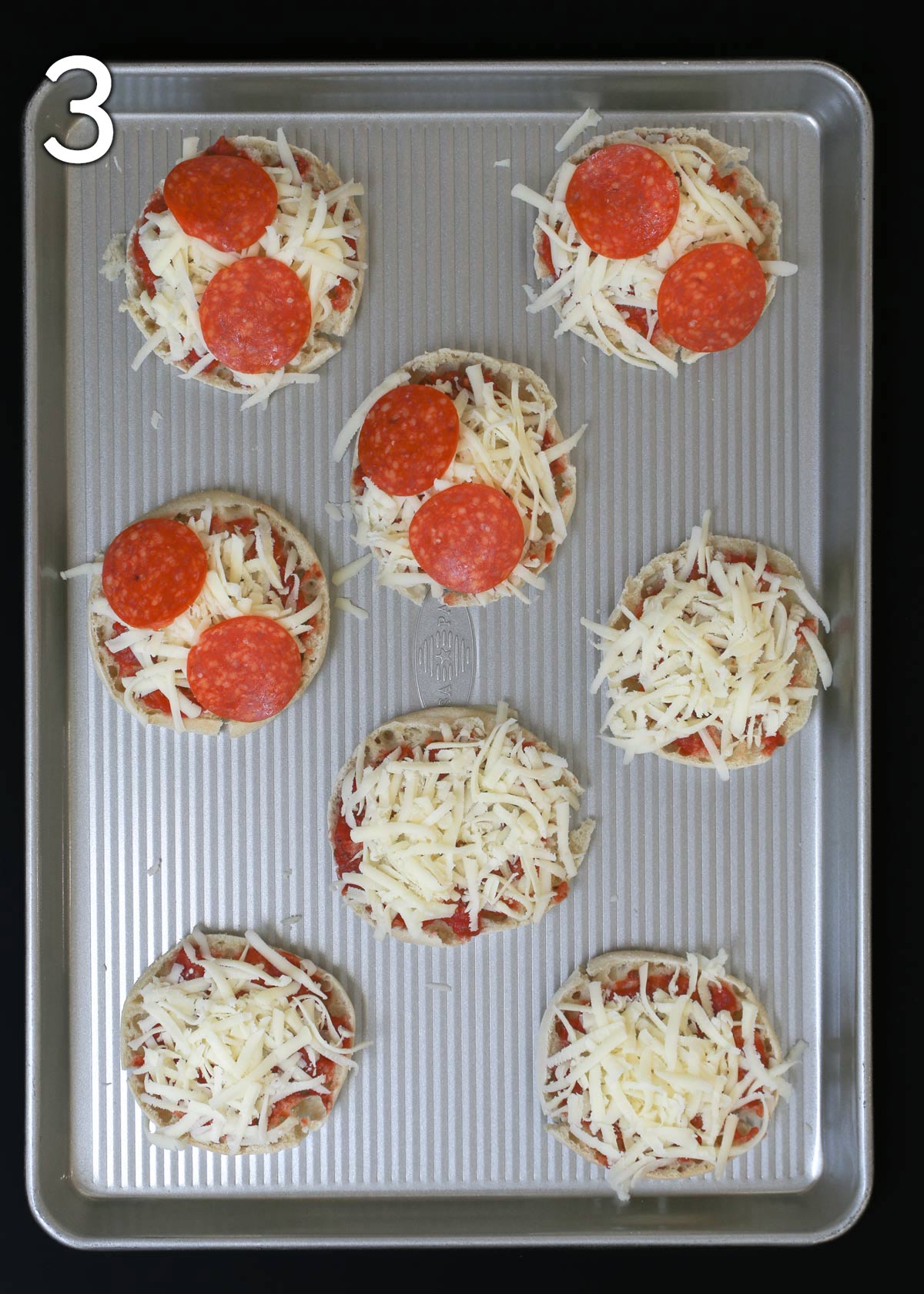 cheese and toppings layered on english muffins.