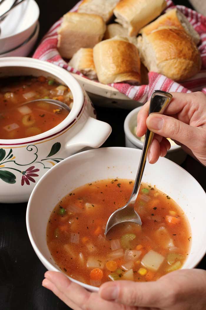 woman stirring bowl of vegetable soup