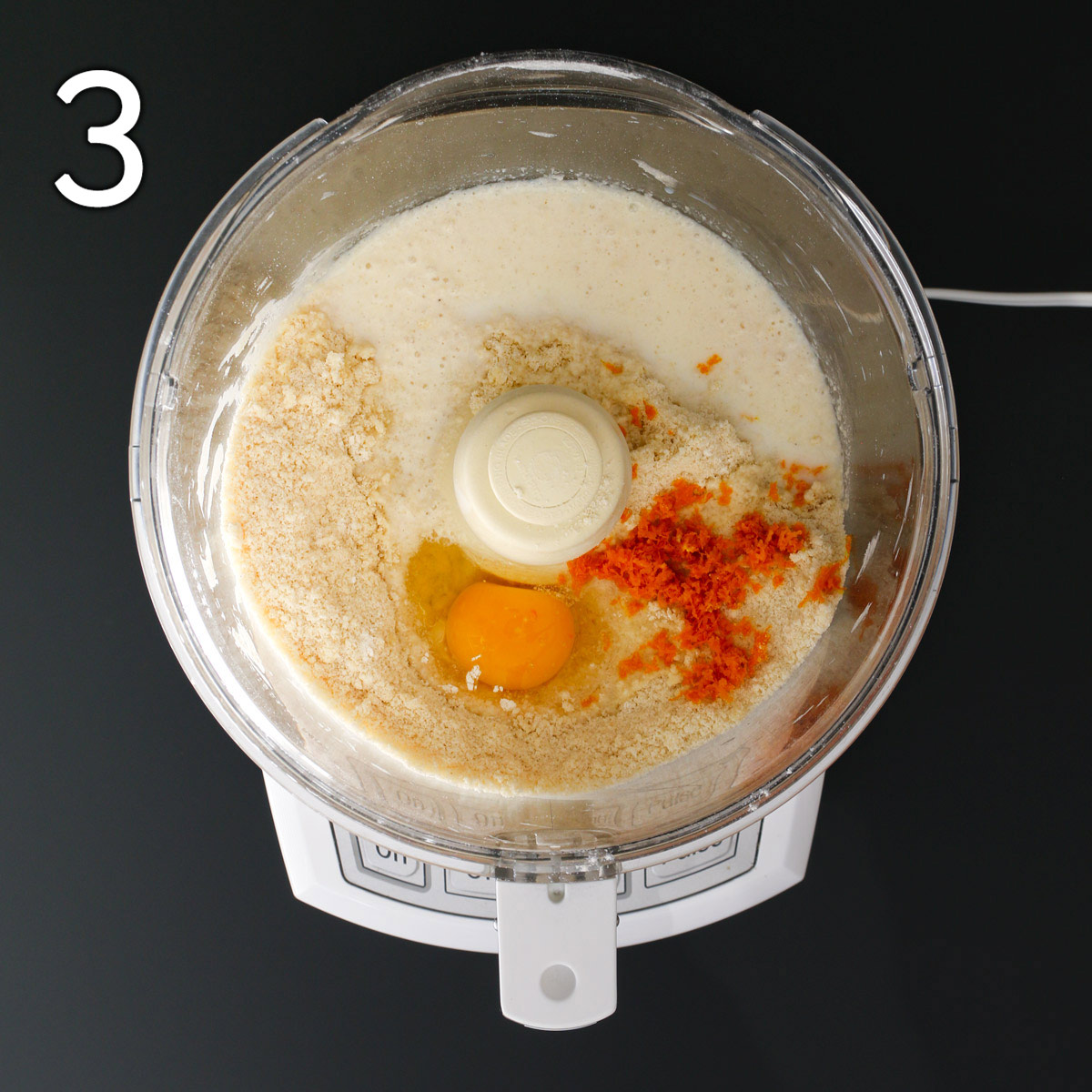 adding egg, milk, and orange zest to crumb mixture in food processor bowl.