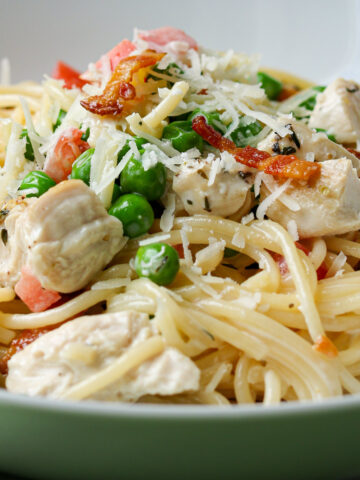 close up of creamy chicken and bacon pasta in bowl.
