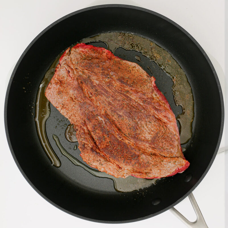 browned chuck roast in skillet with hot oil.