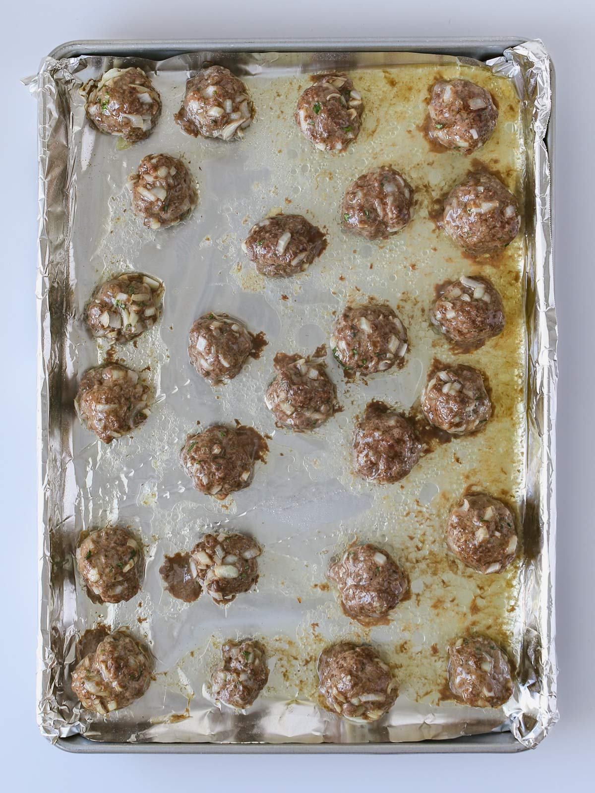 baked meatballs on lined baking sheet.