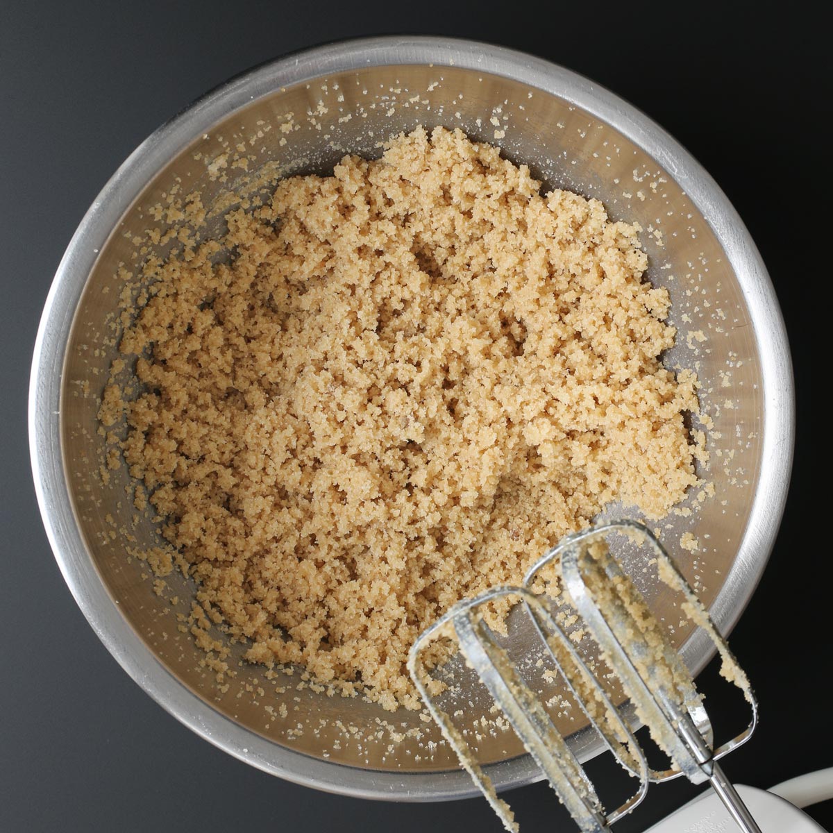 butter and sugar mixture in bowl with hand mixer to the side.