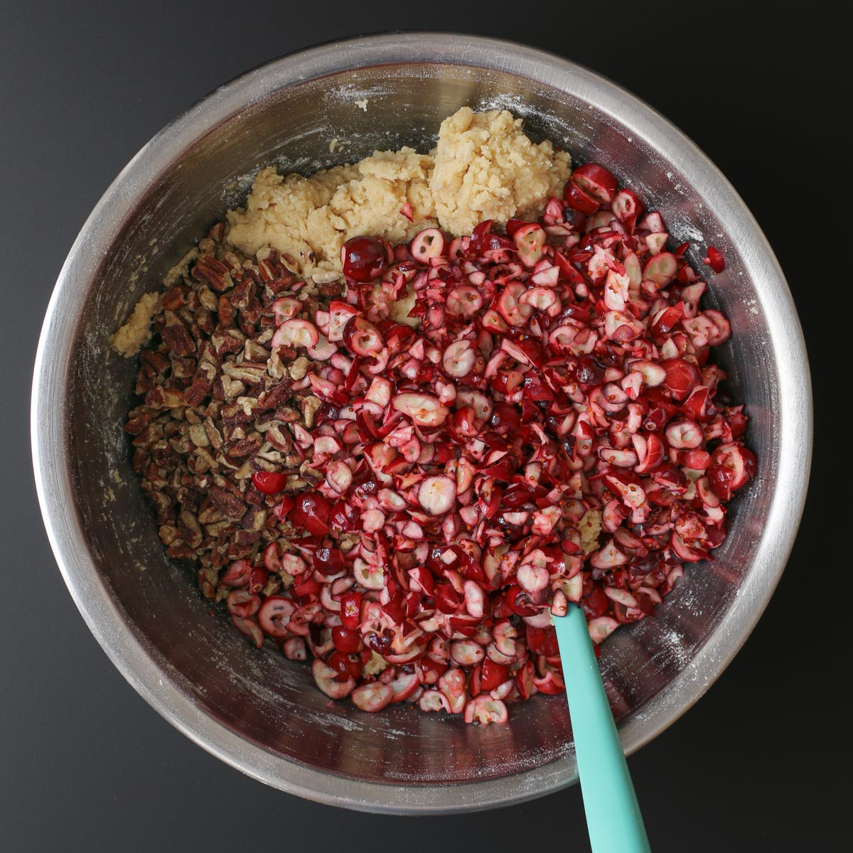 adding cranberries and nuts to the bowl.