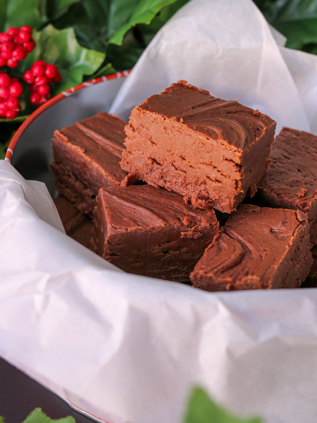 fudge piled into a tin with parchment paper, holly behind.