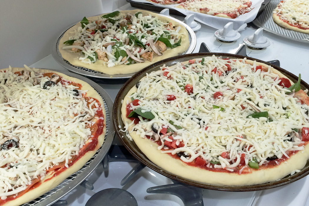 pizzas on trays sitting on stovetop