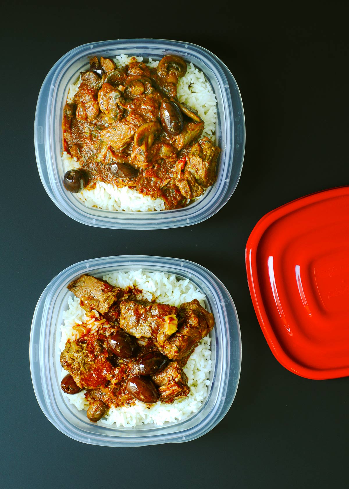 two meal prep boxes with rice and stew with red plastic lids.