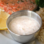 close up of silver cup of remoulade on dinner plate.