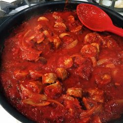 a pot of sausage ragu with red spoon