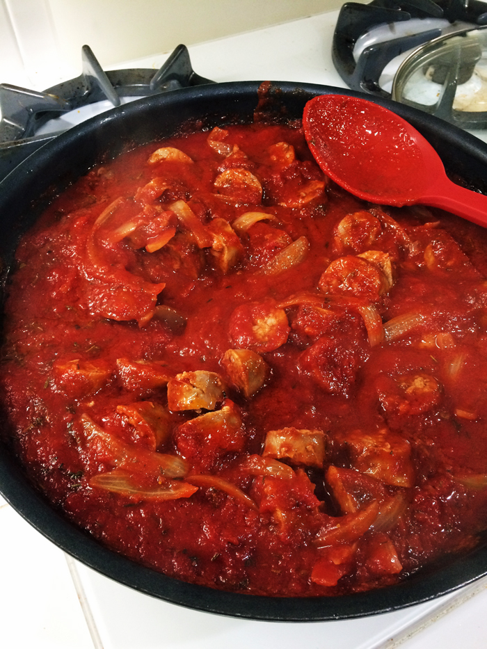 a pot of sausage ragu with red spoon