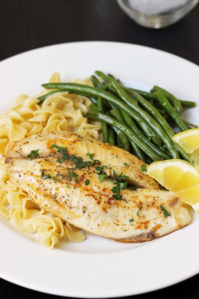 assiette de poisson, nouilles au beurre, haricots verts et tranches de citron