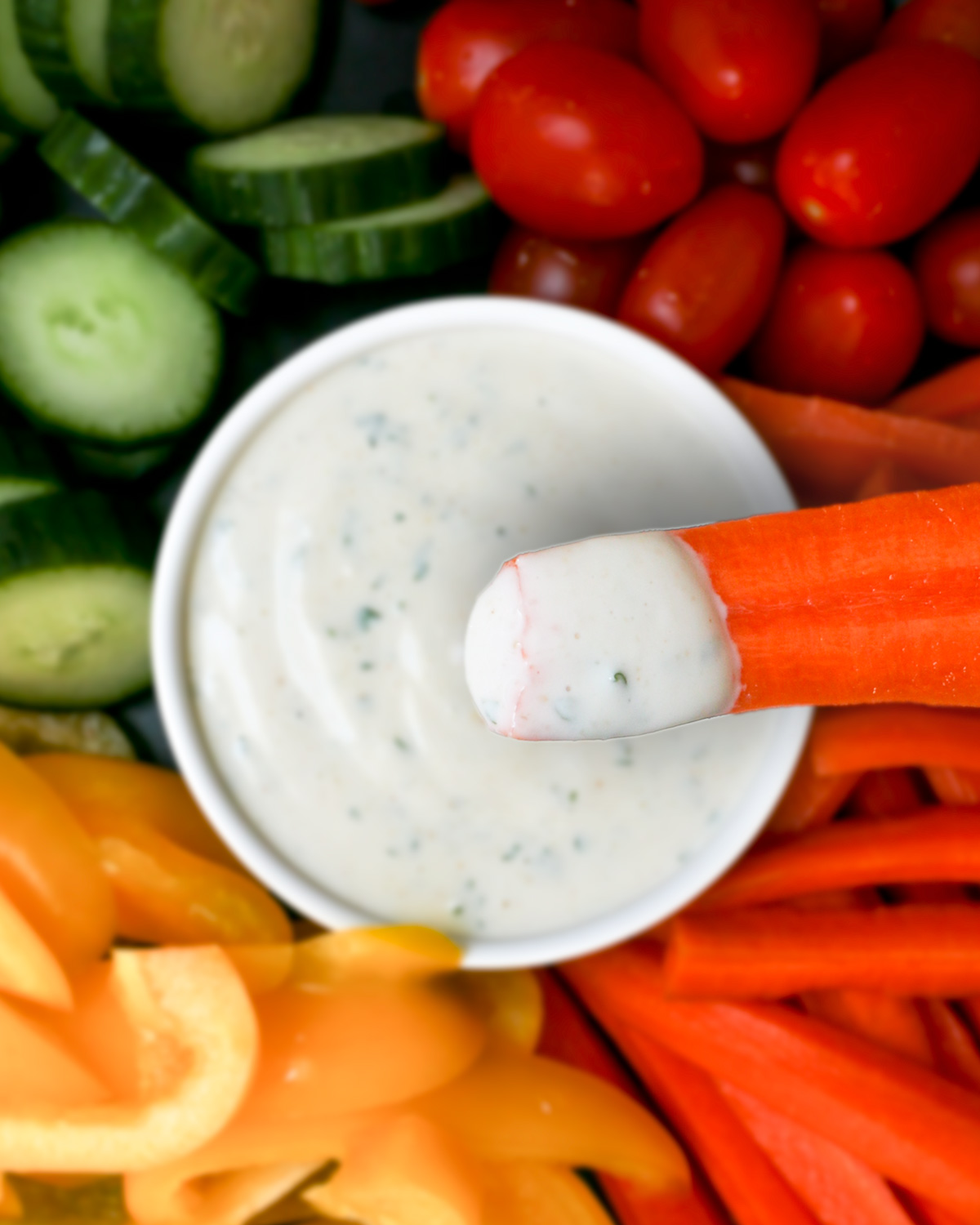 veggie tray with bowl of ranch dip with carrot dipping in.